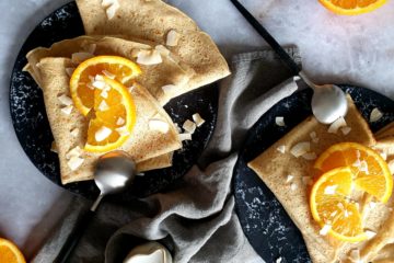 photo culinaire de crêpes à l'orange et à la noix de coco servies avec des oranges et des chips de coco