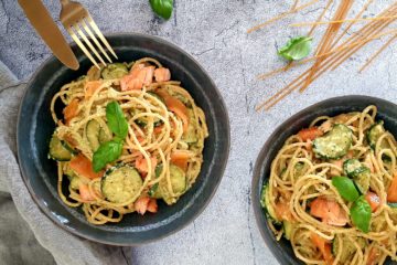 Belle photo d'une assiette de pâtes à la crème de courgettes, courgettes et saumon avec du basilic frais. Photo culinaire colorée et appétissante.