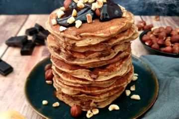 jolie photo d'une pile de pancakes aux pépites de chocolat avec du chocolat fondu et des noisettes