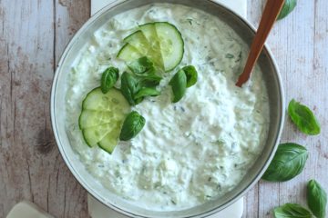 photo culinaire de dip au concombre, feta et citron vert avec de l'aneth et du basilic, servi avec des crackers aux graines