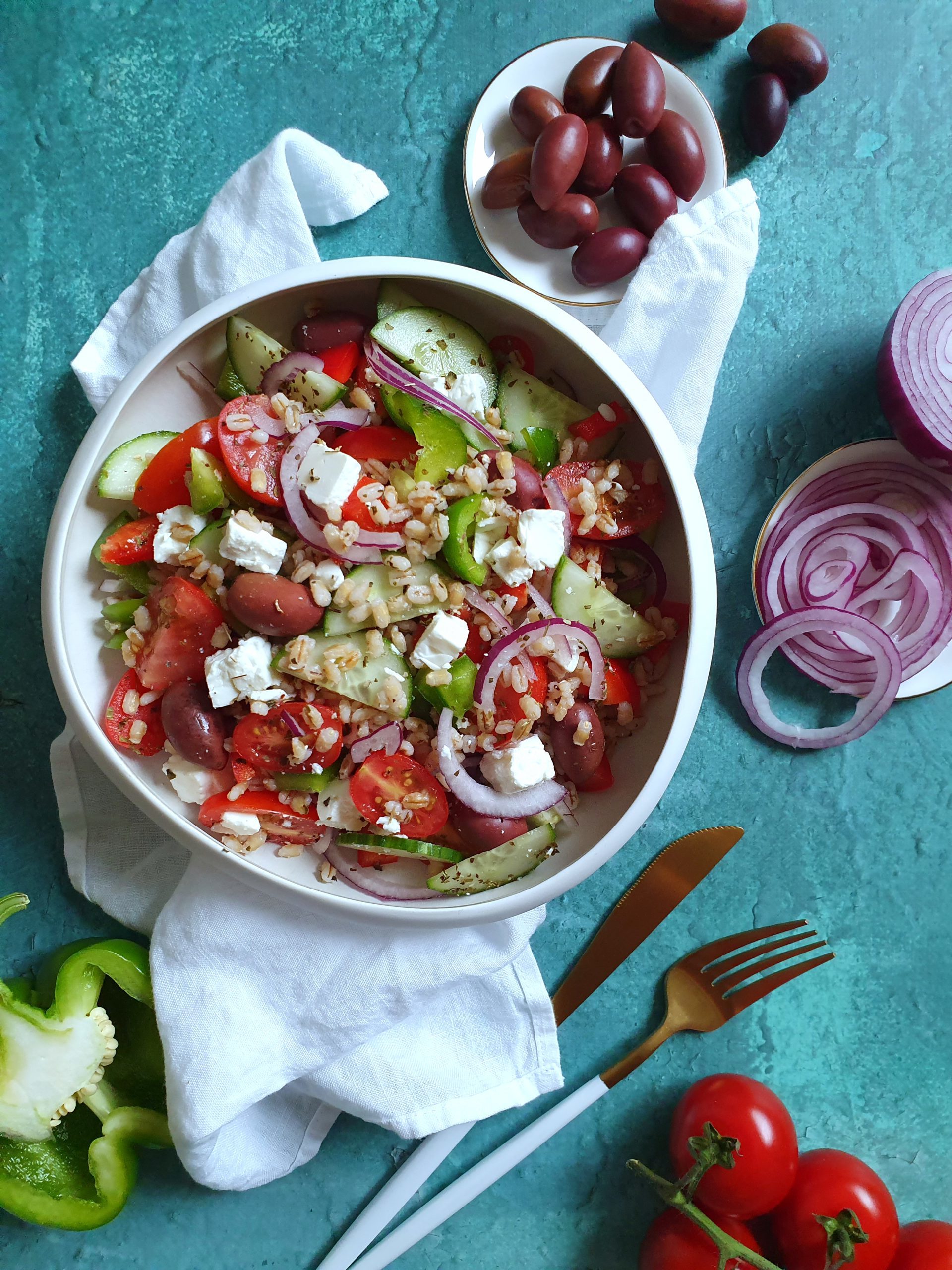photo culinaire d'une salade grecque avec de l'orge monde, assiette colorée sur un fond turquoise