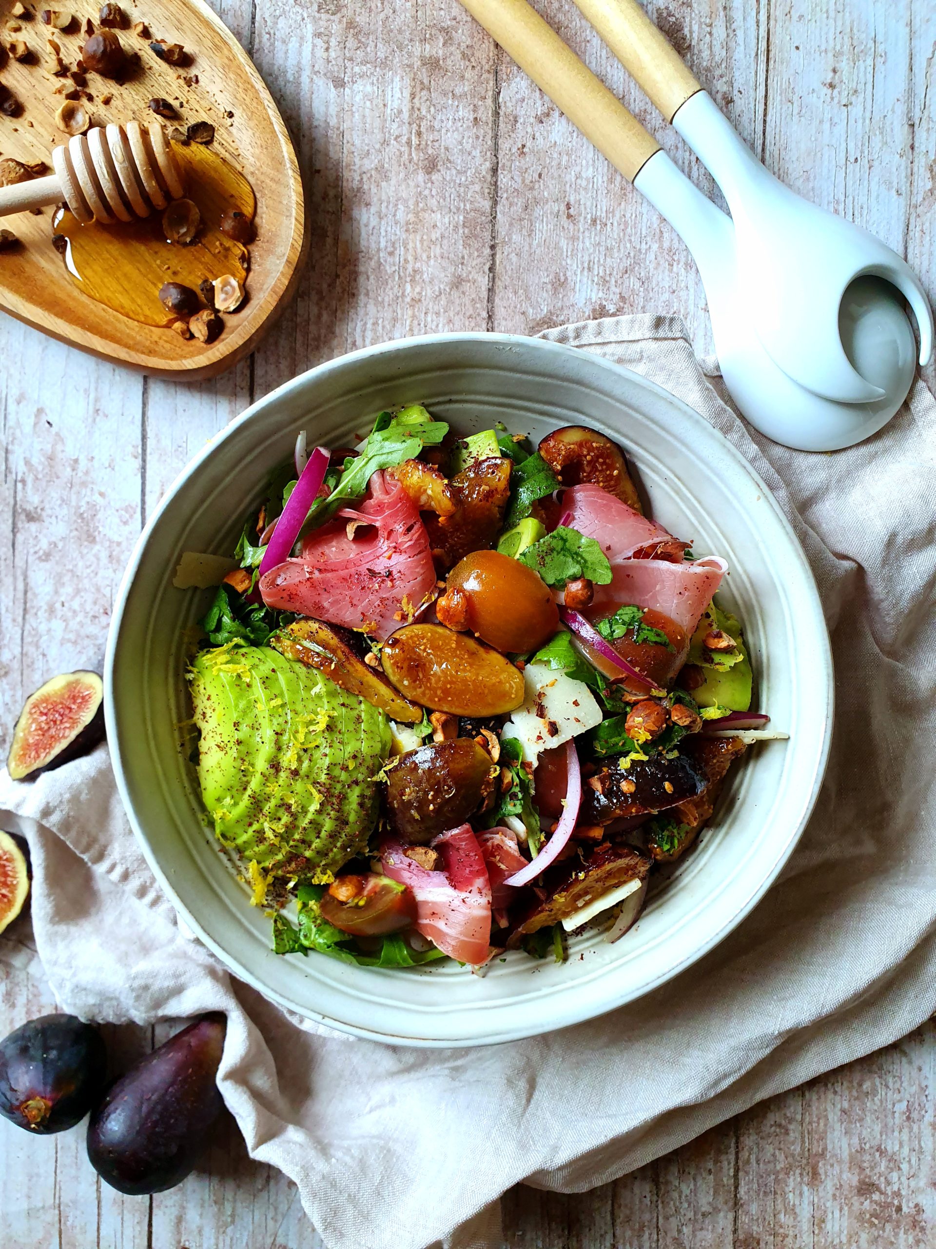 photo culinaire d'une salade de figues rôties avec de l'avocat, du jambon cru et des noisettes torréfiées