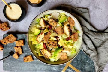 photo culinaire d'une salade caesar heathy au poulet pané avec des croûtons et des copeaux de parmesan