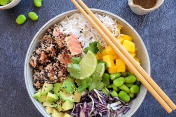 photo culinaire d'un bowl coloré avec du tataki de saumon aux graines de sésame avec de l'avocat, de la mangue et des fèves