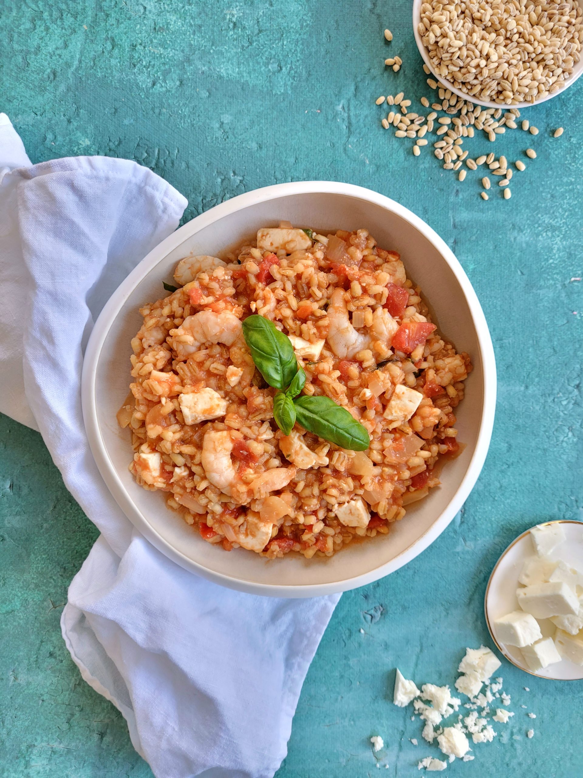 photo culinaire d'un risotto d'orge mondé aux crevettes, tomates et feta avec du basilic