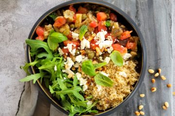photo culinaire d'une salade d'aubergines et tomates aux câpres servie avec du quinoa, de la roquette, de la feta et du basilic