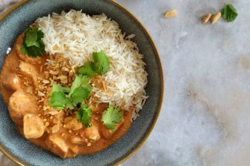 photo culinaire d'un butter chicken avec du riz basmati, des cacahuètes concassées et de la coriandre