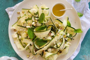 photo culinaire d'une salade de courgettes crues en lamelles avec de la feta, des pistaches et de la menthe