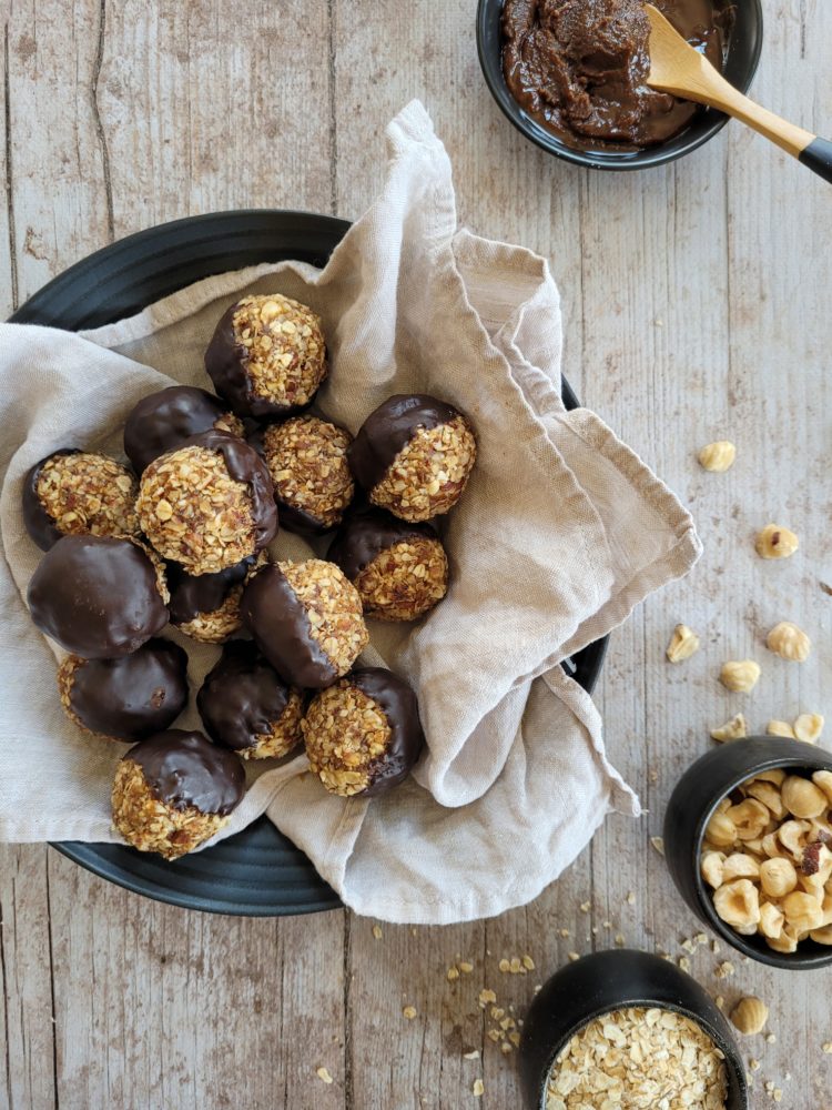 photo culinaire d'energy balls au praliné avec des noisettes et du chocolat noir fondu