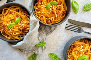 photo culinaire de 3 assiettes de pâtes au pesto de tomates séchées et pignons de pin avec du basilic