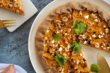 photo culinaire d'une tarte rustique à la patate douce avec de la feta, des noisettes torréfiées et quelques feuilles de coriandre fraîche