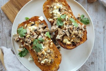 photo culinaire d'une courge butternet farcie aux champignons et crème au tahini avec de la coriandre fraiche, de la feta et des pignons de pin