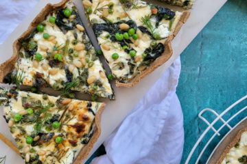 photo culinaire d'une quiche aux épinards, petits pois et citron avec des pignons de pin, de l'aneth et du chèvre frais