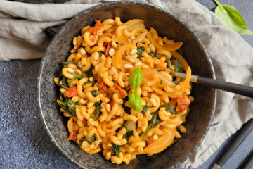photo culinaire d'un one pot pasta aux épinards et tomates séchées avec du parmesan, des pignons de pin et du basilic