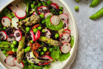 photo culinaire d'une salade de riz noir printanière avec des asperge, des radis, des petits pois et des pousses d'épinards