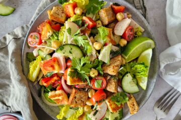 photo culinaire d'une salade fattouche aux pois chiches et halloumi avec du pain grillé au levain et des crudités
