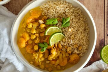 photo culinaire d'un curry de crevettes aux pois chiches et noix de cajou avec du riz complet et du citron vert
