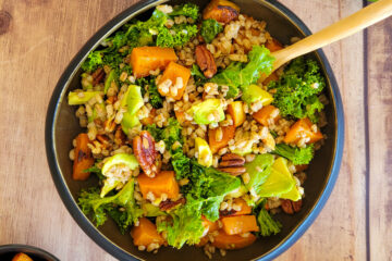 photo culinaire d'une salade d'orge, courge et chou kale avec des noix de pécan, de l'avocat et du citron vert