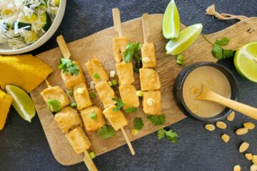 photo culinaire de brochettes de tofu sauce satay avec de la coriandre et du citron vert et servies avec du riz et des courgettes
