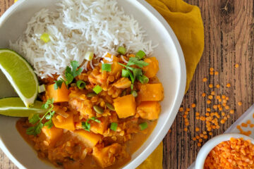 photo culinaire d'un dahl de lentilles corail à la courge avec des graines de courge, du citron vert, de la coriandre et servi avec du riz basmati