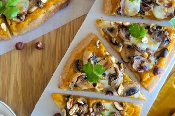 photo culinaire d'une pizza à la courge, champignons et mozzarella avec des noisettes torréfiées et quelques feuilles de coriandre fraîche
