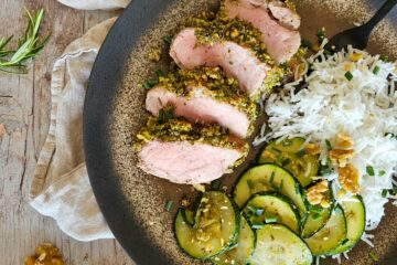 photo culinaire d'un filet mignon en croûte d'herbes et de noix avec du romarin, de la ciboulette et servi avec du riz basmati et des courgettes