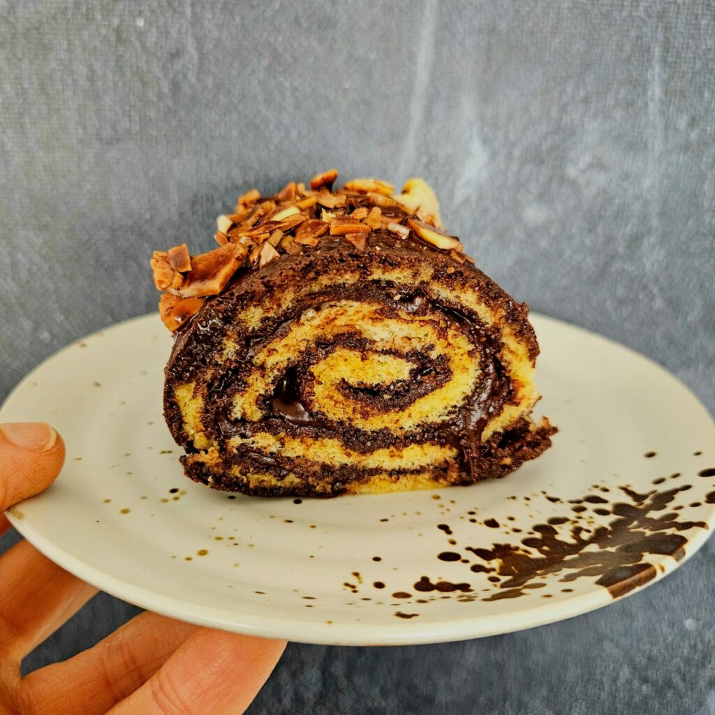 gros plan d'un roulé IG bas au chocolat et aux amandes avec un glaçage à base de chocolat noir et d'amandes effilées