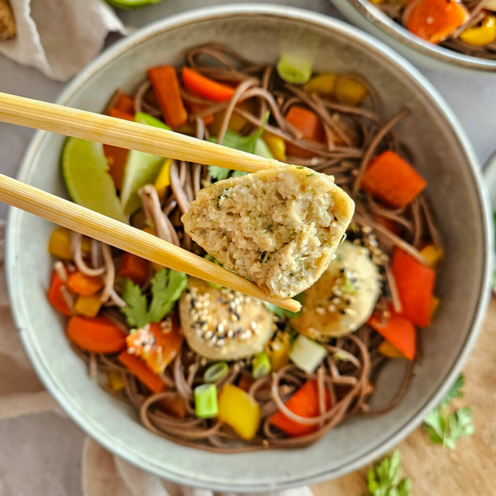 photo culinaire de l'intérieur des boulettes de poulet à l'asiatique avec du gingembre et de la coriandre et servies avec des nouilles soba aux poivrons