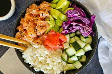 photo culinaire d'un sushi bowl IG bas à base d'un mélange de riz basmati et riz de chou-fleur, de saumon cru, d'avocat, de concombre et de chou rouge