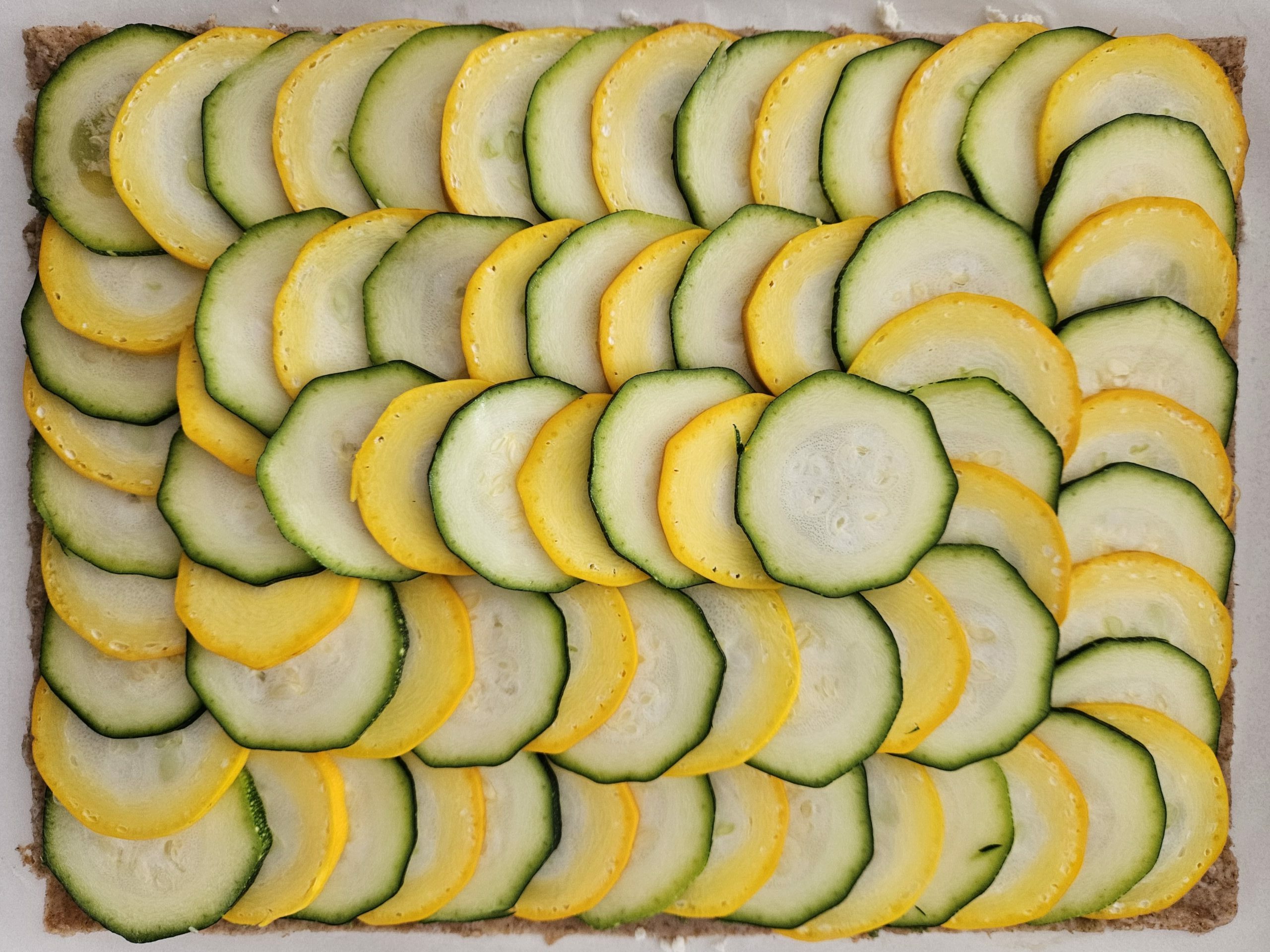 photo de la disposition des rondelles de courgettes sur une tarte fine aux courgettes et pesto