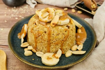 photo culinaire d'un bowl cake à la cacahuète avec des rondelles de banane, de la purée de cacahuètes et des amandes effilées