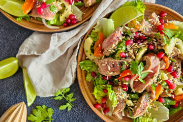 photo culinaire d'une salade de bœuf à l'asiatique avec de la coriandre, des graines de sésame, de la sauce soja, du citron vert et des graines de grenade