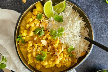 photo culinaire d'un curry de chou-fleur et pois chiches avec du riz basmati, des amandes effilées, de la coriandre fraîche et du citron vert