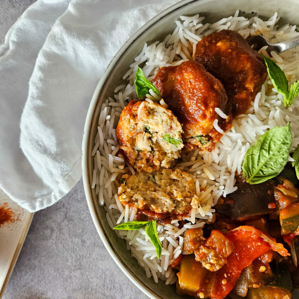 photo culinaire de l'intérieur des boulettes de poisson à la provençale avec du poisson blanc, du basilic, des tomates séchées et de la sauce tomate.
