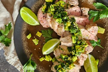photo culinaire d'un filet mignon de porc sauce chimichurri à l'avocat avec du persil, de l'ail, du citron vert, de l'origan et des morceaux d'avocat