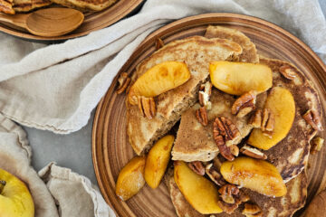 photo culinaire de pancakes aux pommes caramélisées avec de la pomme râpée à l'intérieur et par dessus des quartiers de pommes caramélisées et des morceaux de noix de pécan