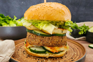 photo culinaire d'un burger veggie avec un steak veggie quinoa, champignons et haricots rouges avec du halloumi, du guacamole et des rondelles de concombre