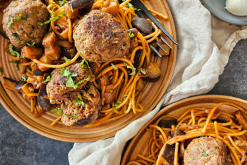 photo culinaire de boulettes de bœuf à l'italienne avec de la mozzarella, des tomates séchées, du basilic et servies avec des pâtes aux aubergines et à la sauce tomate