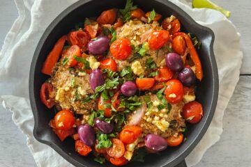 photo culinaire d'un poulet à la grecque avec de la feta, des tomates cerise et poivrons rôties, du sumac, de la menthe, du persil et du citron vert