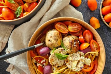 photo culinaire de boulettes de poulet à la grecque servies avec des pâtes intégrales aux poivrons, tomates cerise, olives et feta