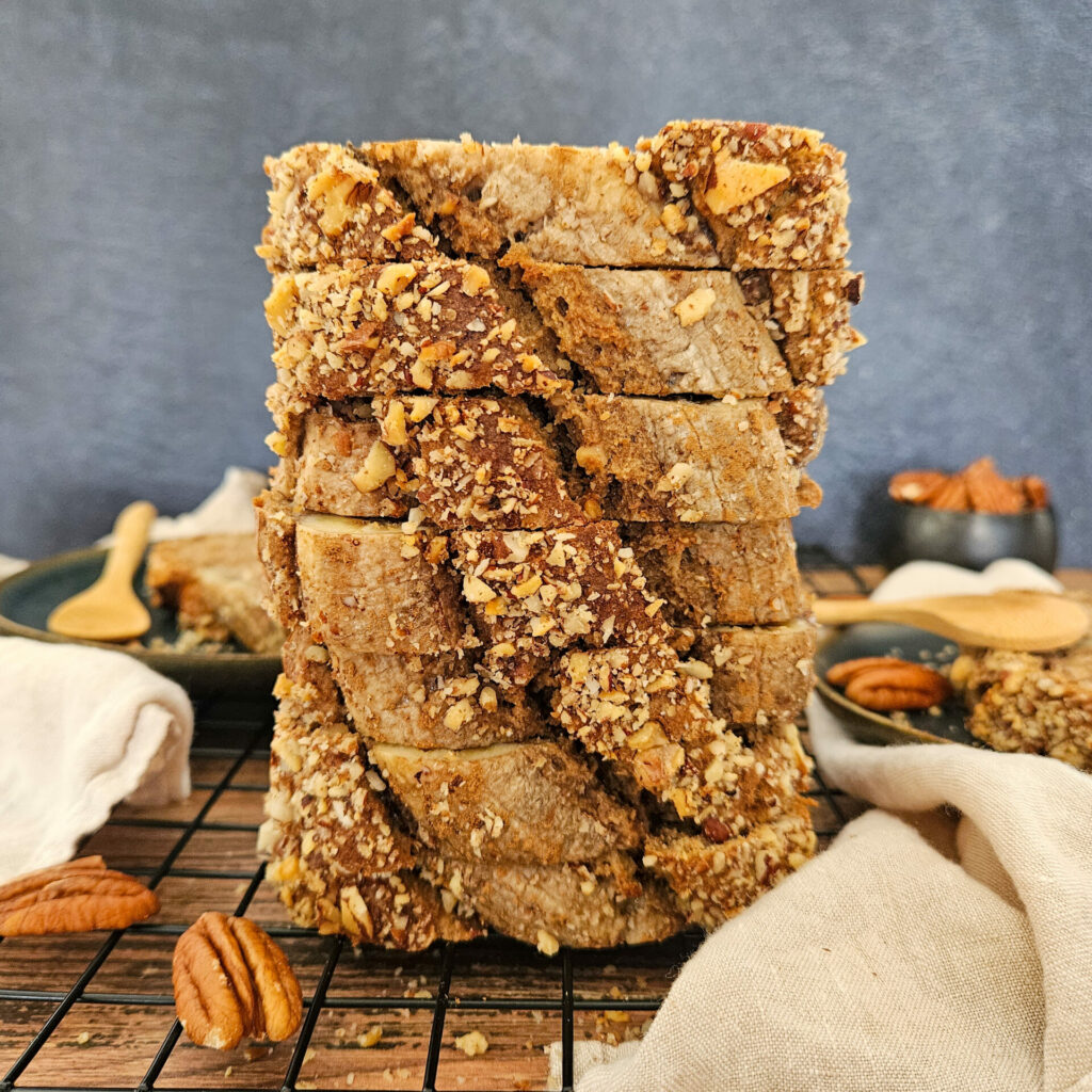 photo culinaire d'une pile de tranches de banana bread à la cannelle et noix caramélisées avec des noix de pécan, noix du Brésil et noix