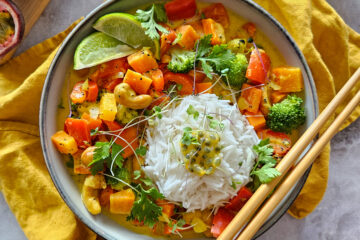 photo culinaire d'un curry aux fruits de la passion avec des légumes : carottes, poivrons et brocolis servi avec du riz basmati, des noix de cajou et du citron vert