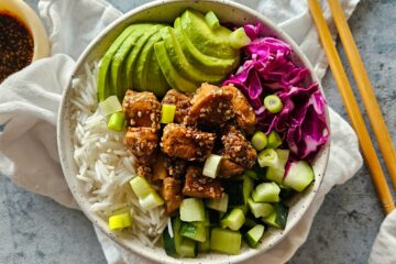 photo culinaire d'un bowl de poulet yakitori avec du riz basmati, des dés de concombre, de l'avocat, du chou rouge, des cébettes et de la coriandre