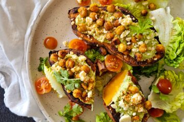 photo culinaire de patate douce farcie à l'avocat, pois chiches et feta avec de la salade verte et des tomates cerise