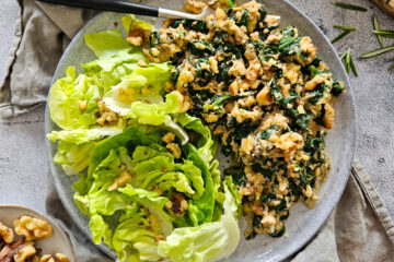 photo culinaire d'œufs brouillés aux épinards, bleu et noix avec du romarin et servis avec de la salade verte