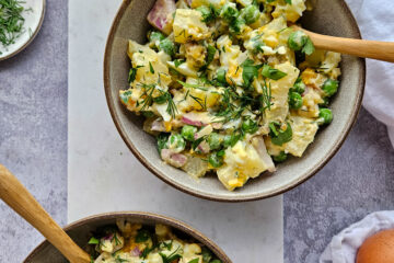 photo culinaire d'une salade de pommes de terre et oeufs avec des petits pois, des câpres, du citron confit, de l'aneth, du persil et des oignons rouges