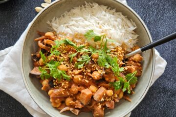 photo culinaire d'un mijoté d'aubergines, pois chiches et cacahuètes avec de la purée de cacahuètes, des éclats de cacahuètes et de la coriandre