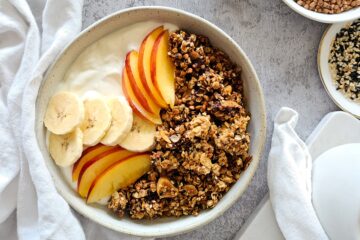 photo culinaire d'un granola sarrasin chocolat et sésame avec du tahiini, du kasha, des noix du brésil et des amandes effilées servi avec des fruits et du yaourt grec