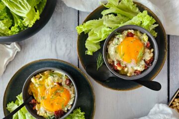 photo culinaire d'œuf cocotte aux poireaux, chèvre et tomates séchées avec des pignons de pin et servis avec de la salade