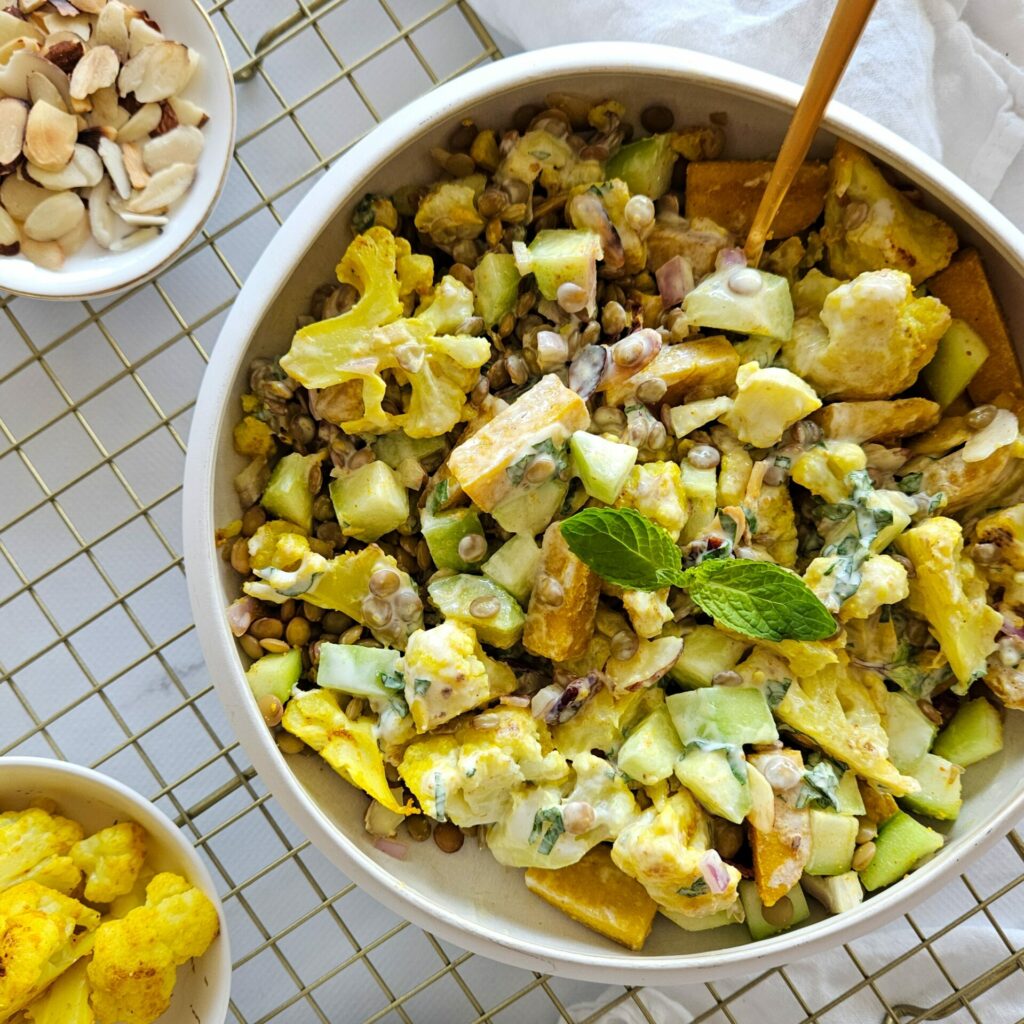 photo culinaire une salade de lentilles, chou-fleur et tofu au curry mélangée avec une sauce au yaourt au miel et à la menthe